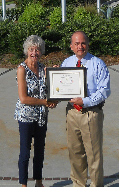 President Bill Price presents a flag certificate to Genie Ostle, Assistant to the General Manager at Bald Head Island Club
